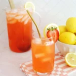 Glass pitcher and glass of pink strawberry lemonade over ice