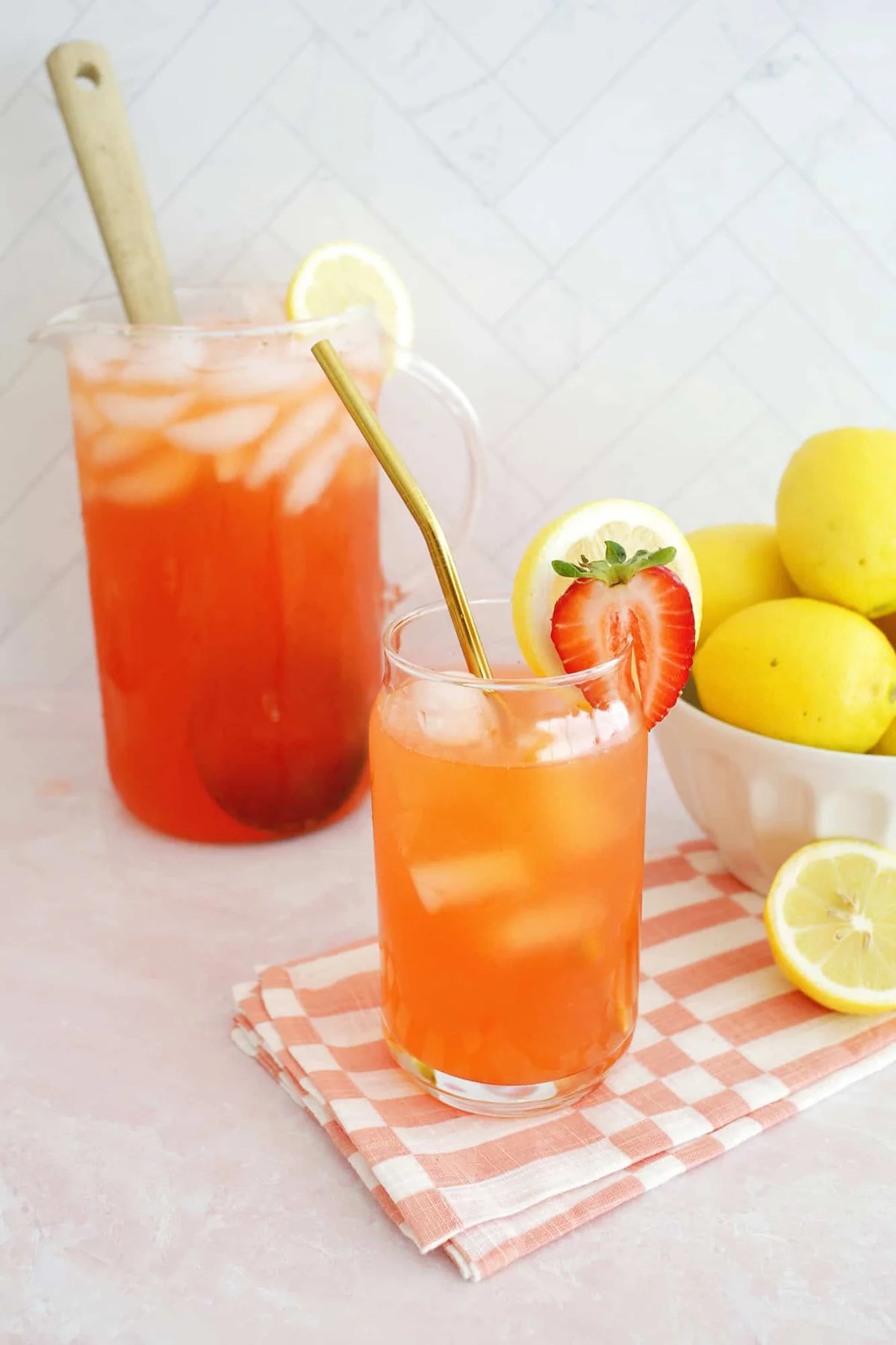 Glass pitcher and glass of pink strawberry lemonade over ice