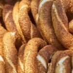 Sesame-covered koulouri bread rings on a counter next to Greek coffee