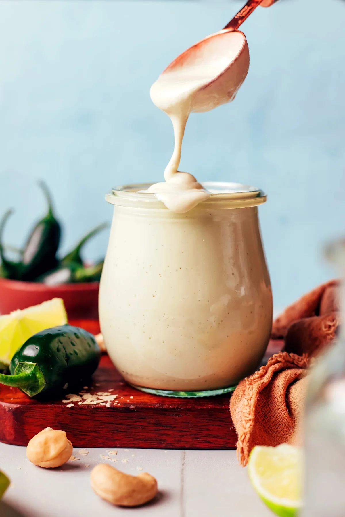Creamy cheesy jalapeño cashew dressing being poured from a spoon into a jar