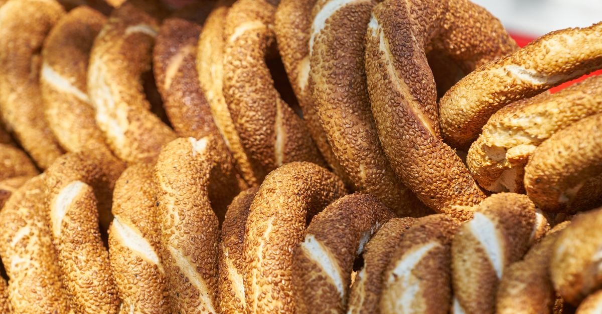 Sesame-covered koulouri bread rings on a counter next to Greek coffee