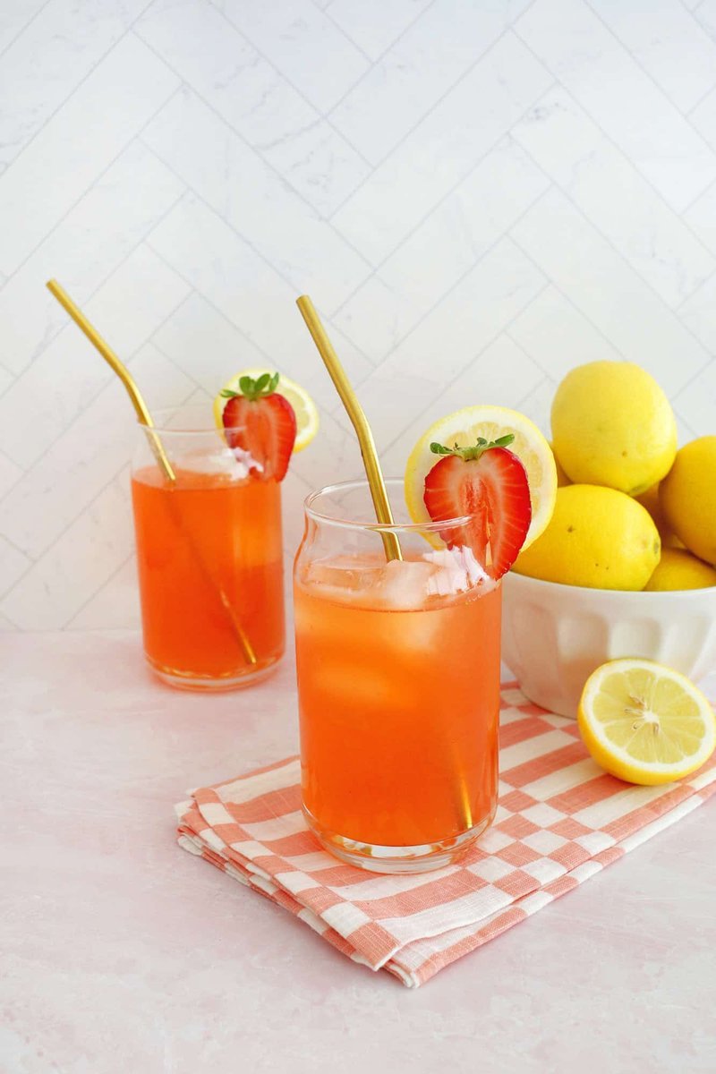 Two glasses of strawberry lemonade garnished with lemon and strawberry