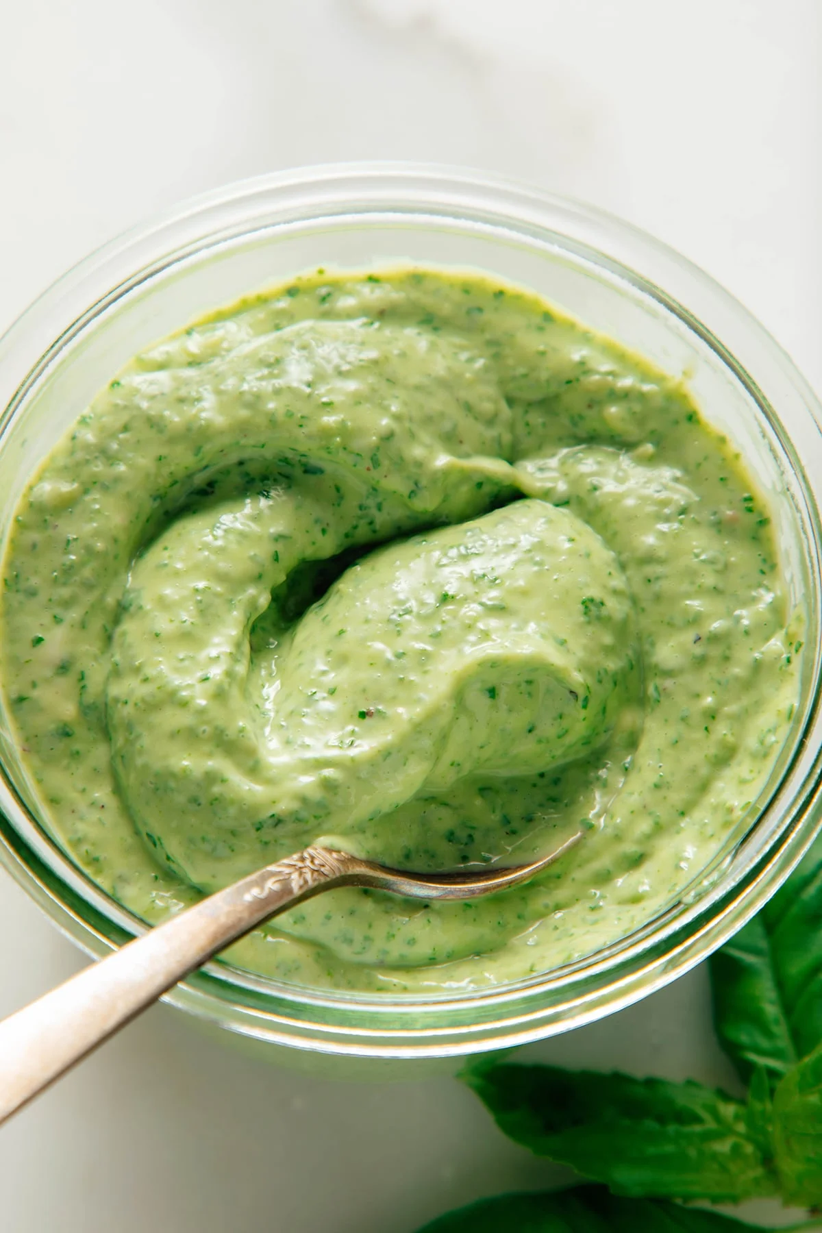 Smooth green basil sauce swirling in a bowl