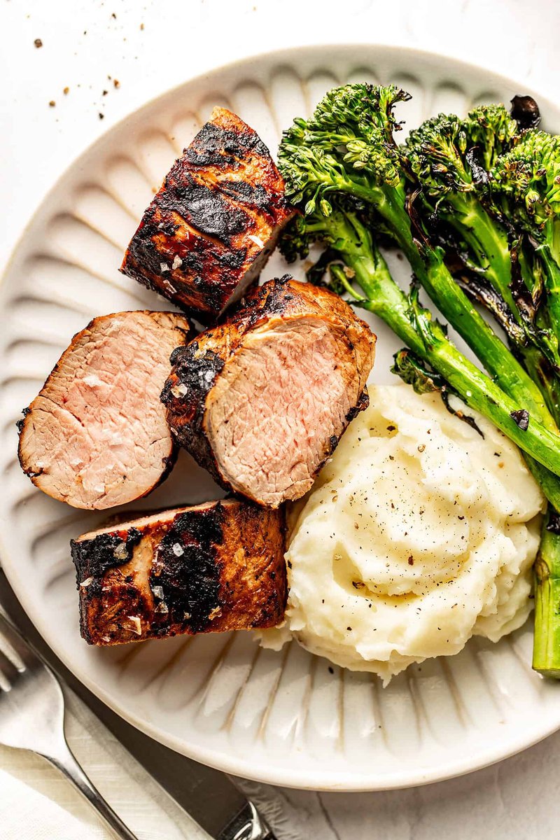 Sliced grilled pork tenderloin plated with mashed potatoes and roasted broccoli