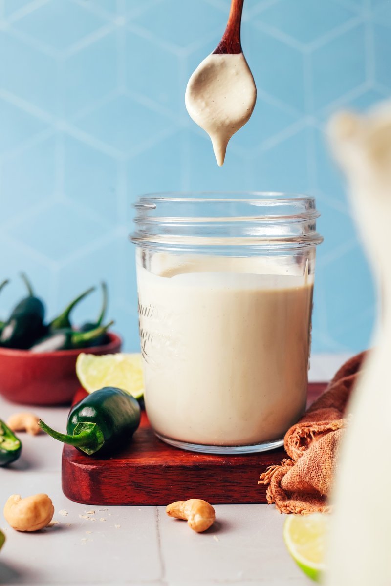 Finished creamy cashew dressing in a jar with a wooden spoon