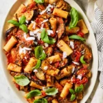 Platter of pasta alla Norma with eggplant, tomato sauce, basil, and grated cheese