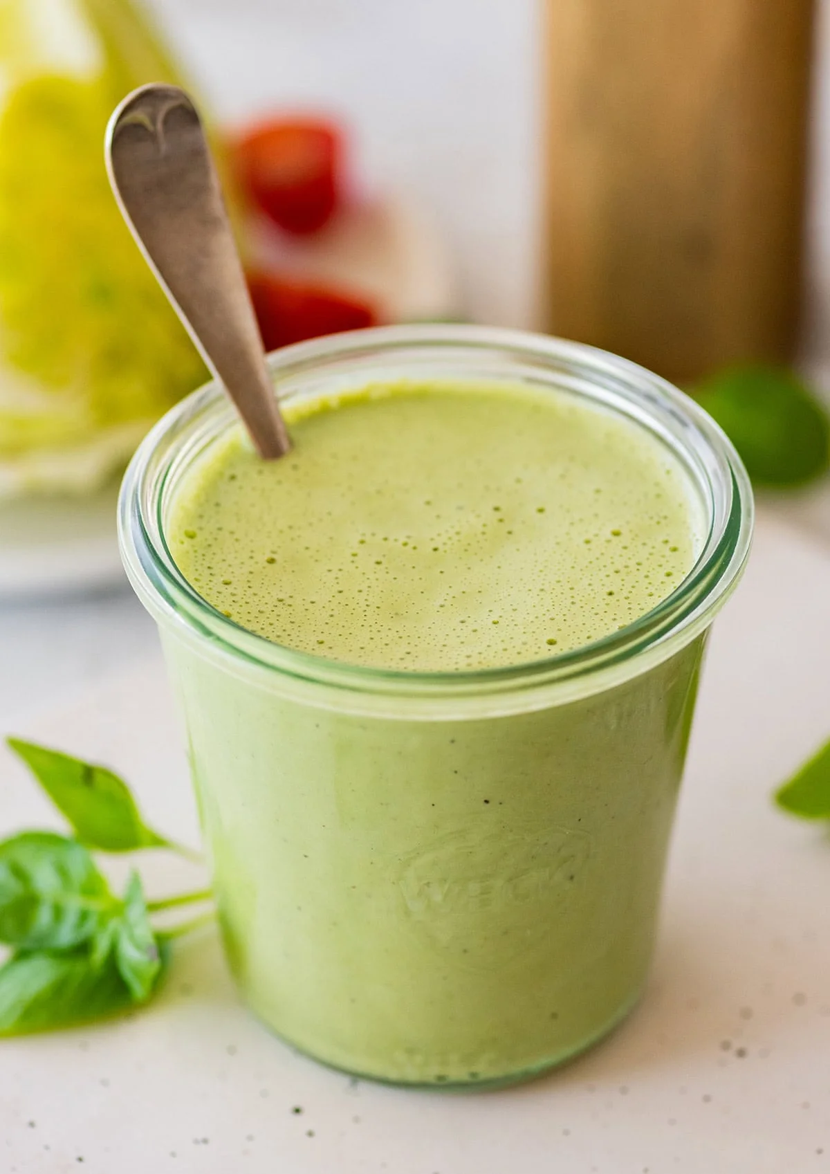 Creamy green goddess dressing in a glass jar with fresh basil