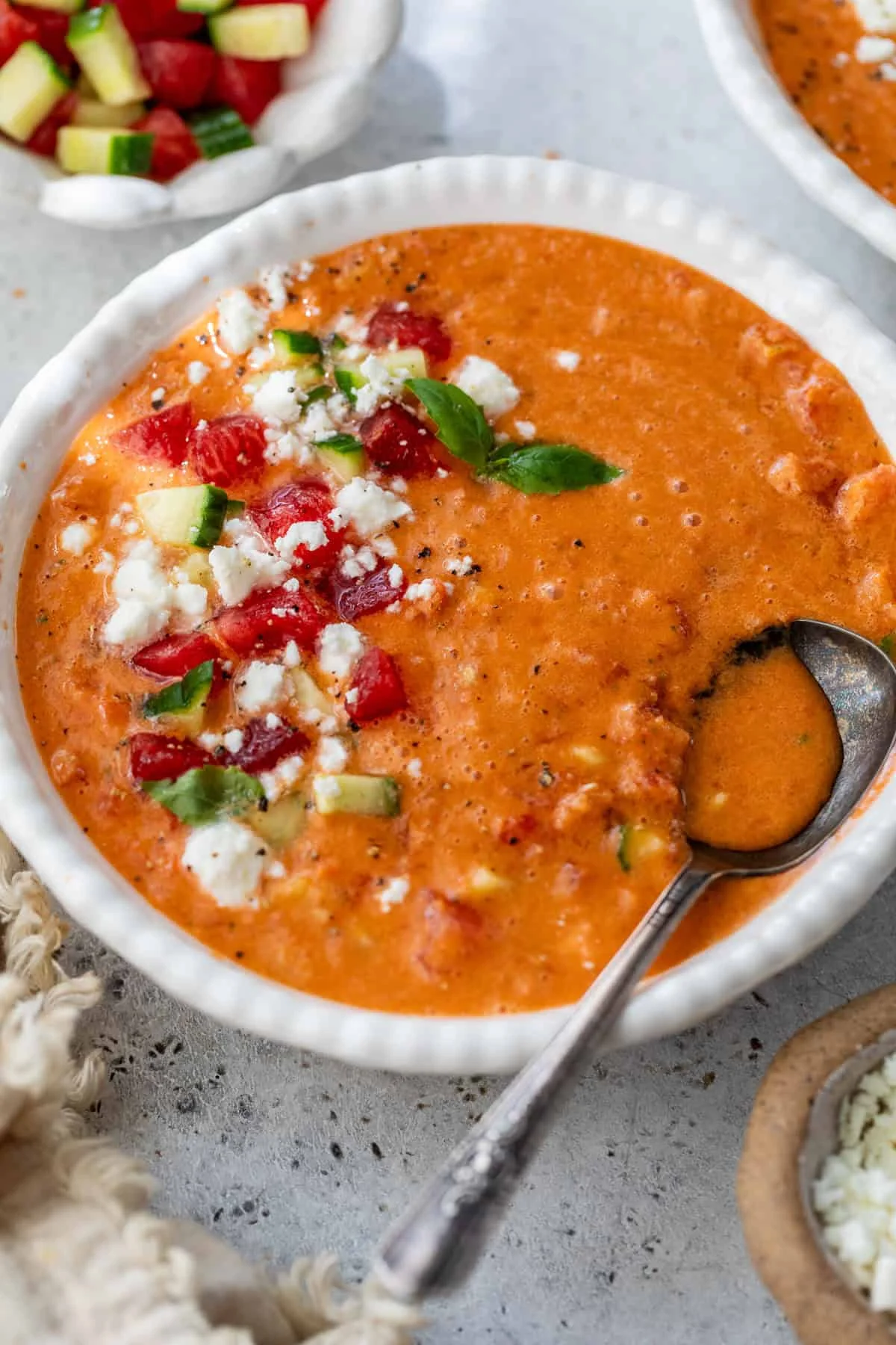 Bowl of cold watermelon gazpacho topped with feta, watermelon, cucumber, and basil