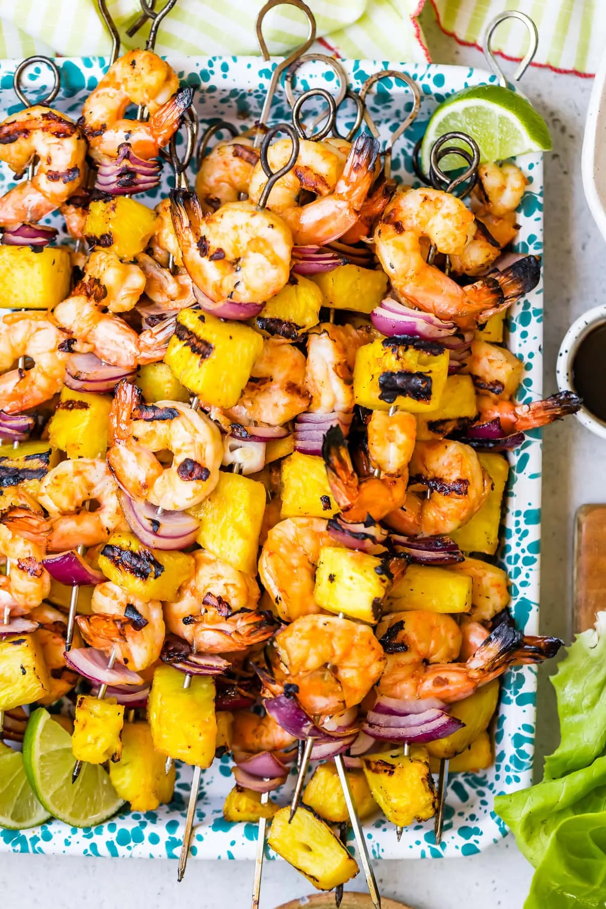 Grilled shrimp and pineapple skewers with red onion, limes, and dipping sauce