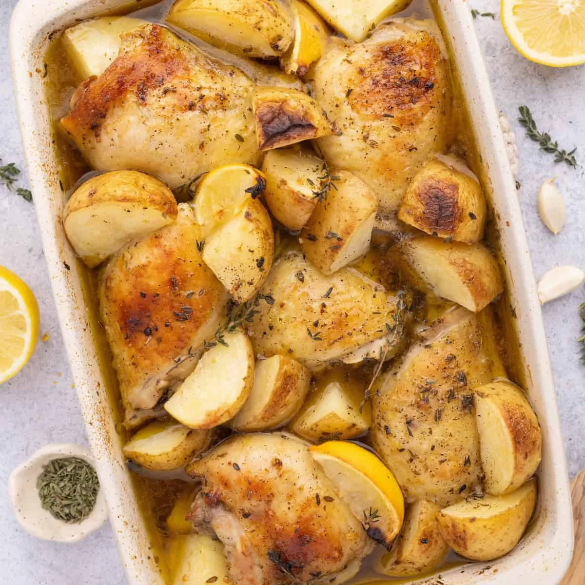 Baked Greek chicken thighs and potatoes with lemon in a baking dish
