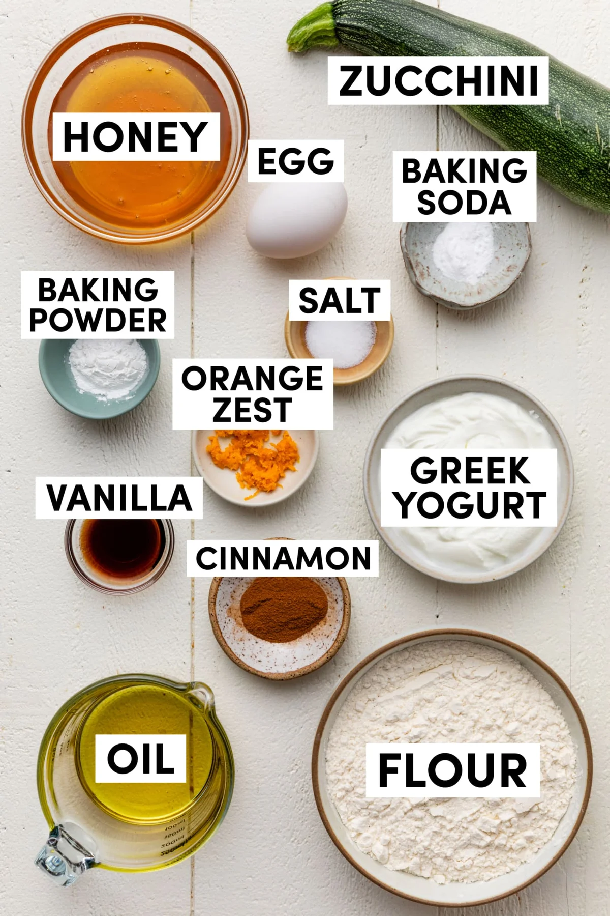 Labeled baking ingredients for Greek yogurt zucchini bread in a flat lay