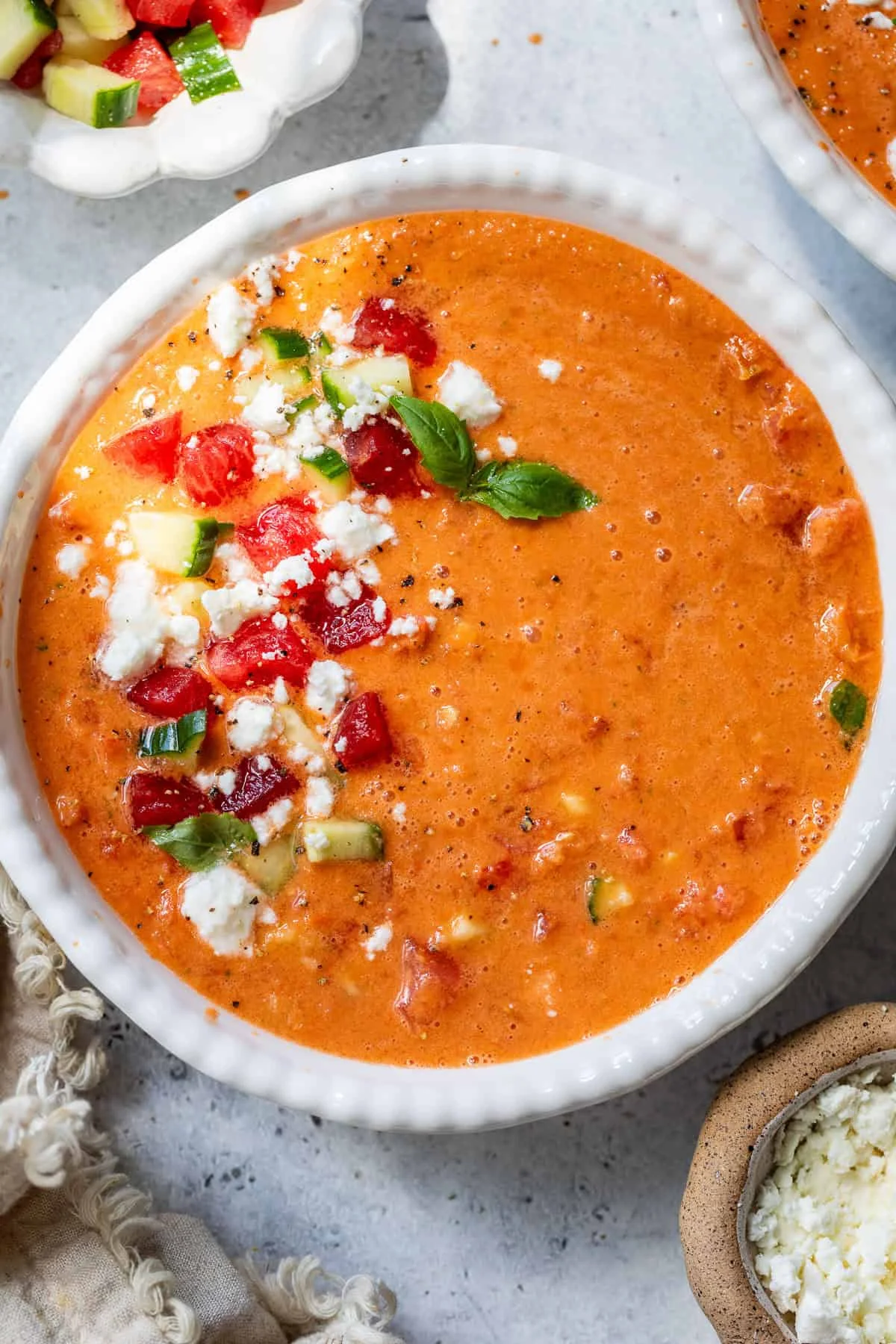 Top-down view of finished watermelon gazpacho bowl with feta and herb garnish