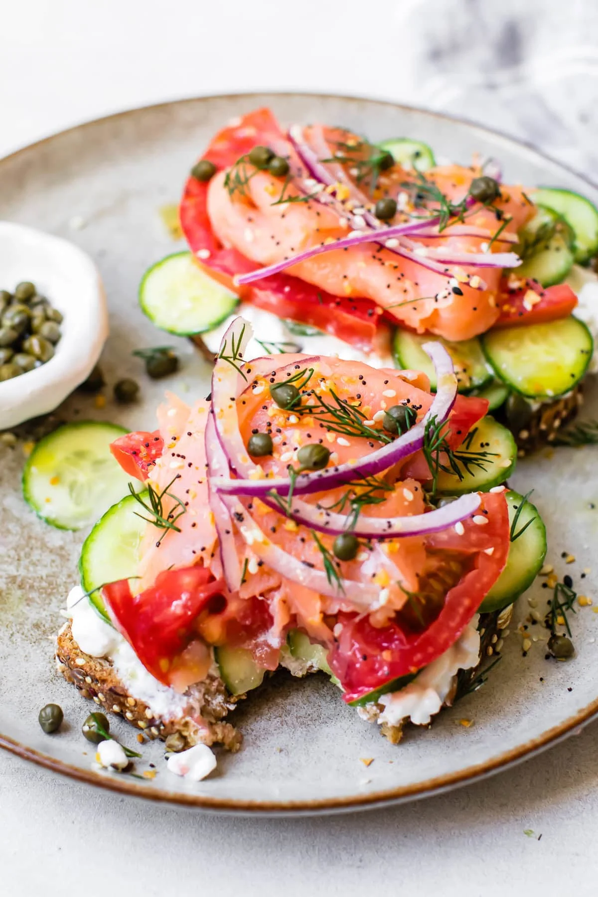Stacked smoked salmon toast with cucumbers and tomato on toast
