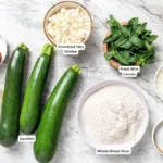 Labeled ingredients for zucchini fritters on a marble surface