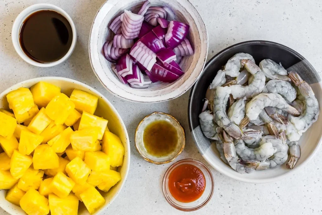 Pineapple, red onion, shrimp, and glaze ingredients arranged on a counter