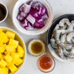 Pineapple, red onion, shrimp, and glaze ingredients arranged on a counter
