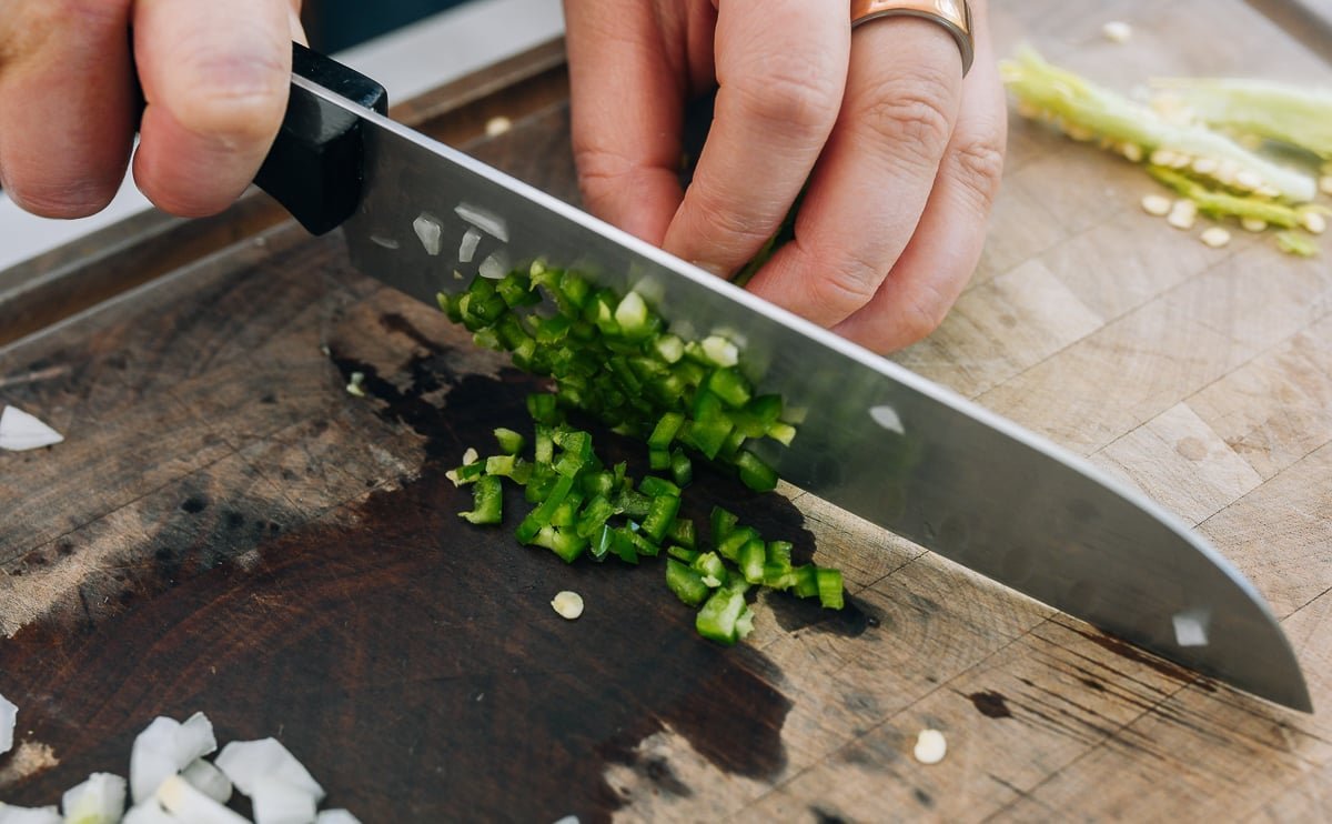 Finely diced jalapeño and white onion on a wooden cutting board