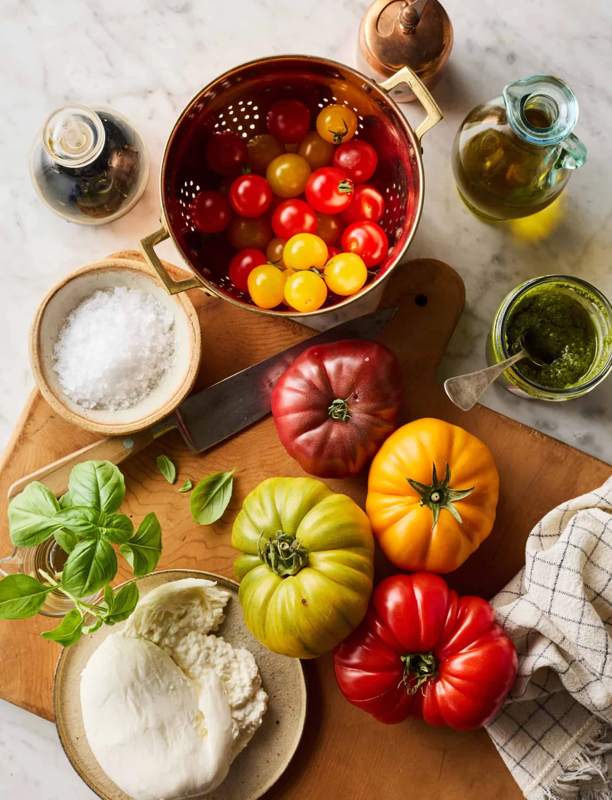 Fresh burrata, heirloom tomatoes, basil, and pesto on a counter