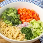 Raw ingredients arranged in sections: penne, broccoli, pepper, cucumber