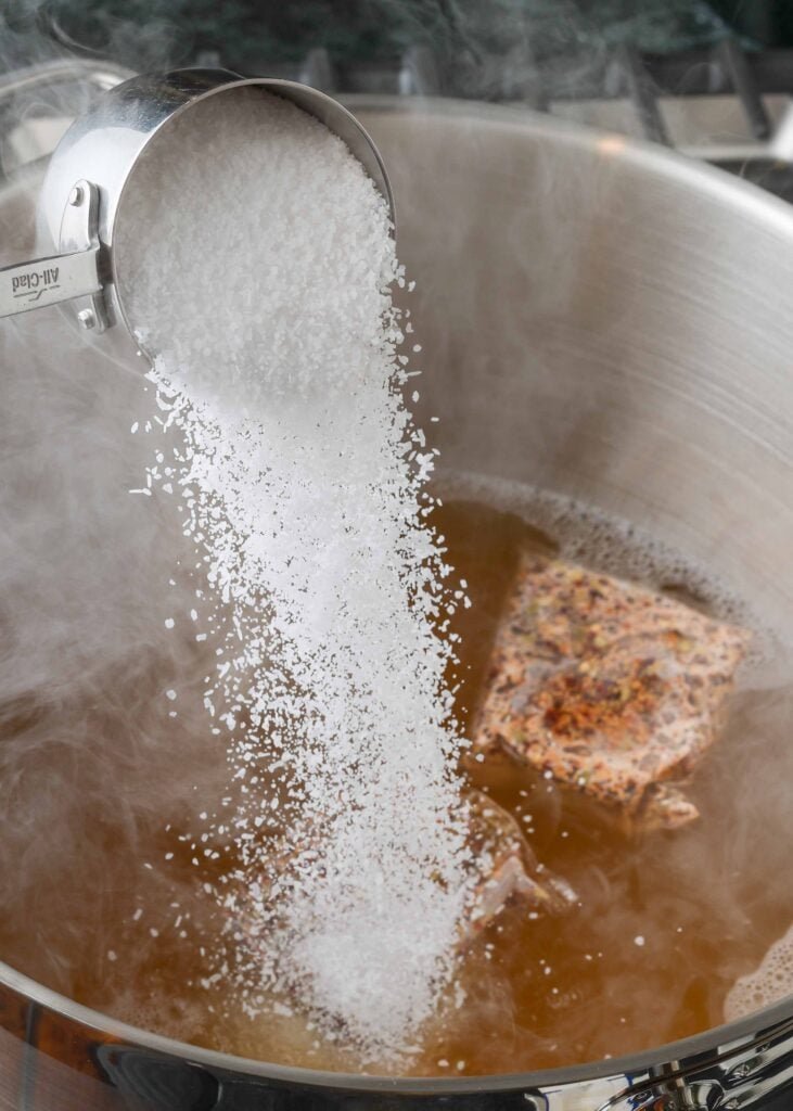 Salt and seasonings stirred into a bubbling shrimp boil