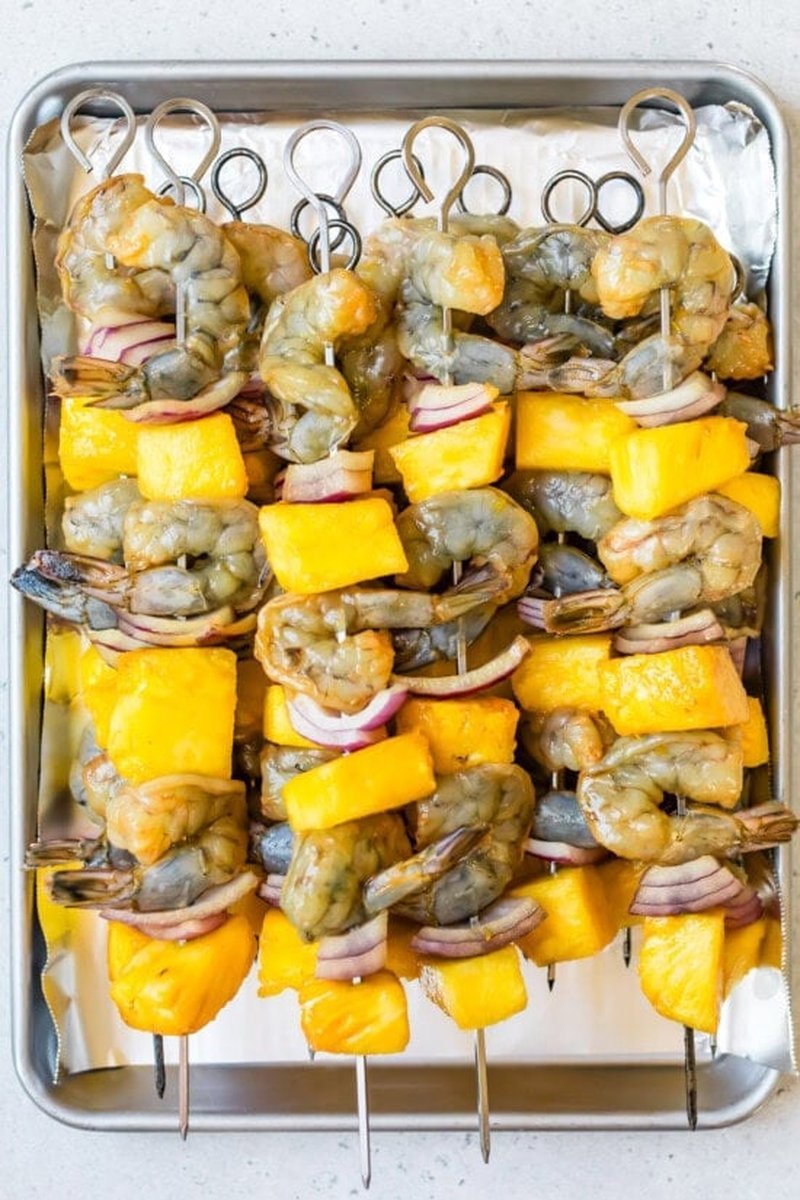 Raw shrimp, pineapple, and onion threaded onto metal skewers