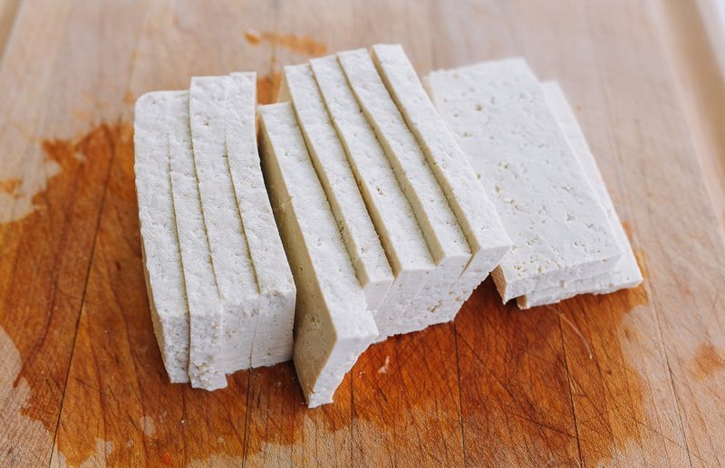 Tofu slices being coated in cornstarch before frying