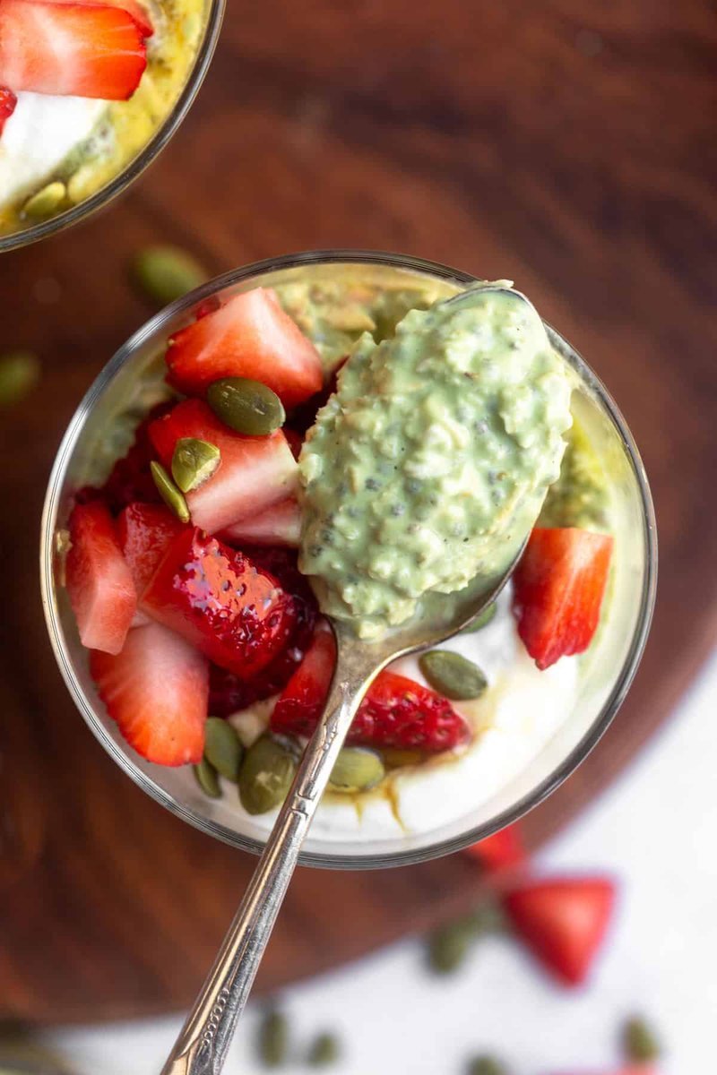 Spoon lifting creamy matcha oats from a glass bowl