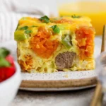 Slice of sweet potato breakfast casserole with melted cheddar on a plate