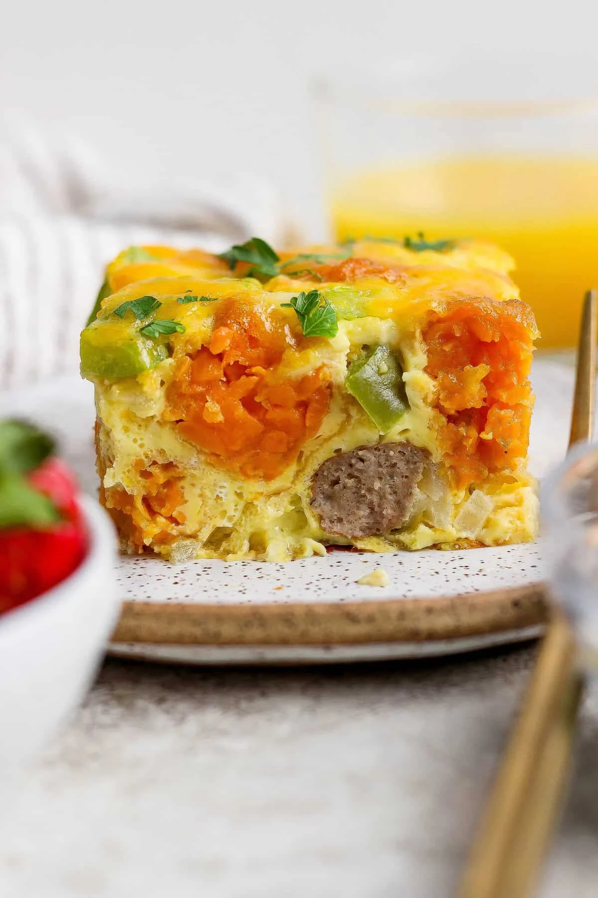 Slice of sweet potato breakfast casserole with melted cheddar on a plate