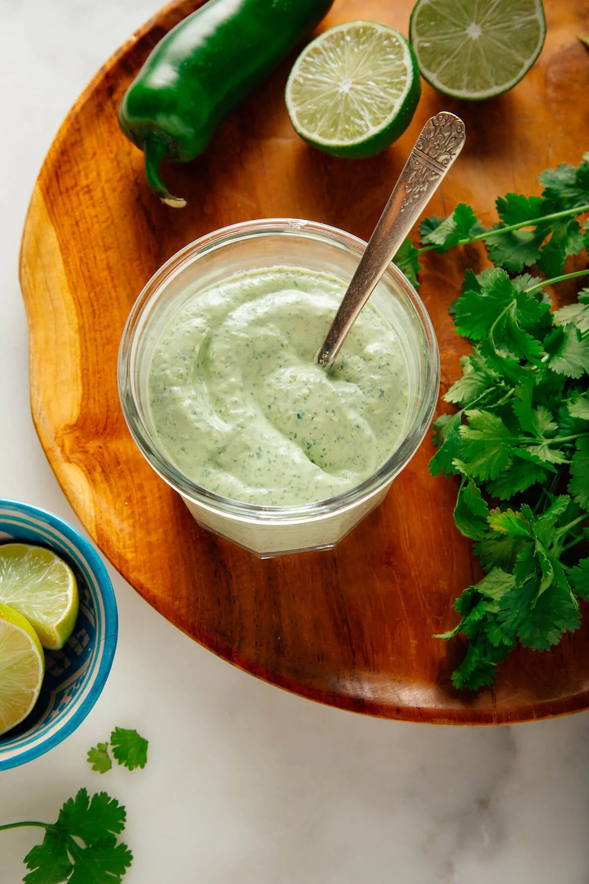 Jar of creamy cilantro lime sauce with limes and cilantro