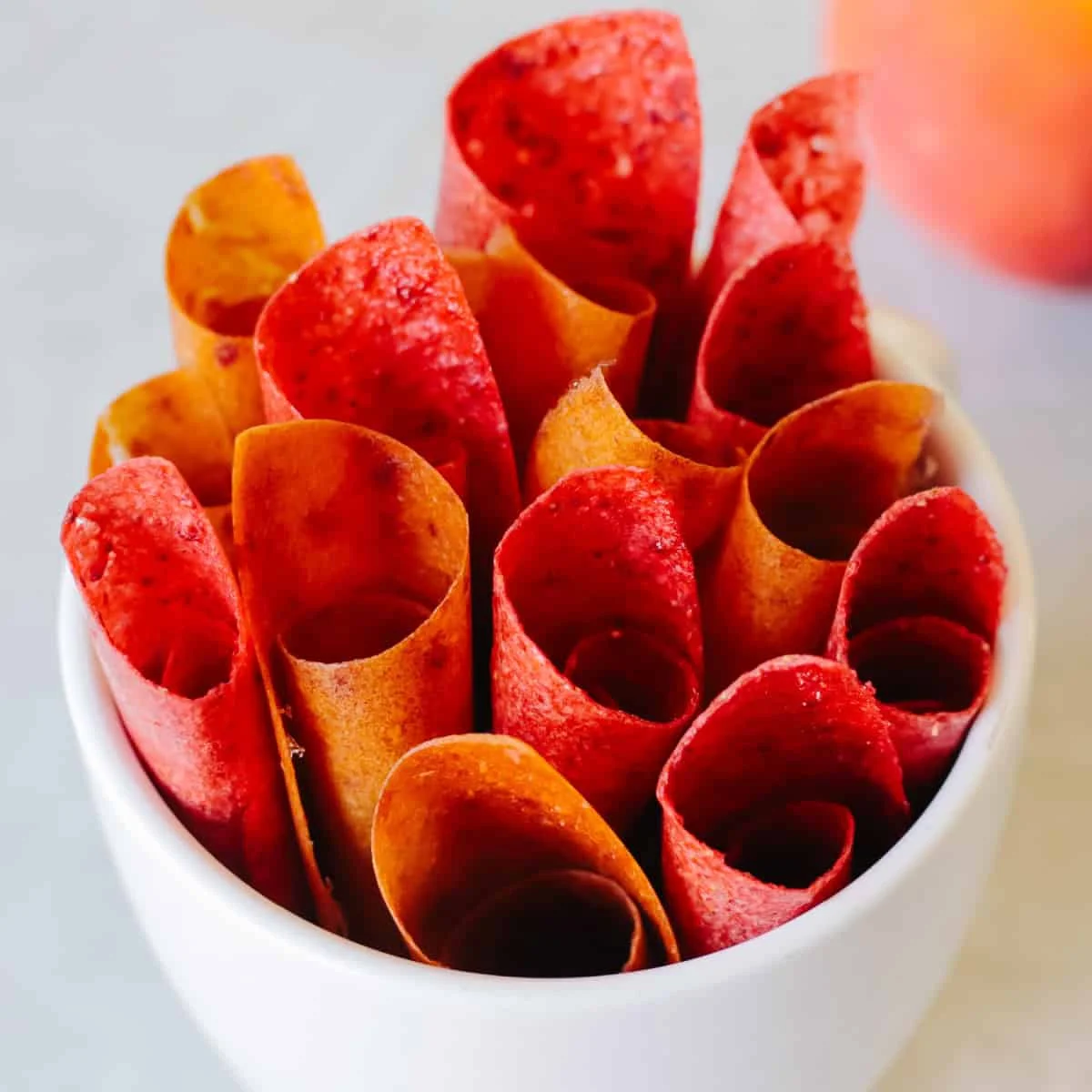 Rolls of homemade strawberry fruit leather on a kitchen counter