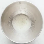 Frothy egg whites just starting to whip in a steel bowl