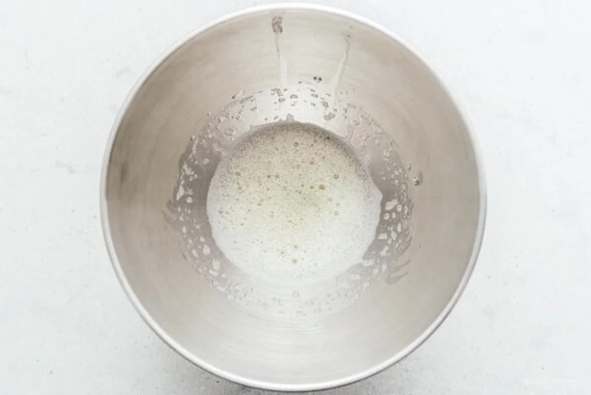 Frothy egg whites just starting to whip in a steel bowl