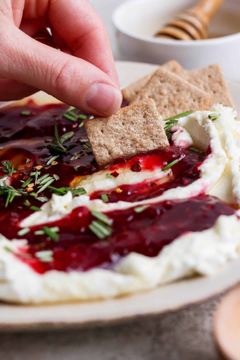 Finished layered dip topped with hot honey, red pepper flakes, and fresh herbs