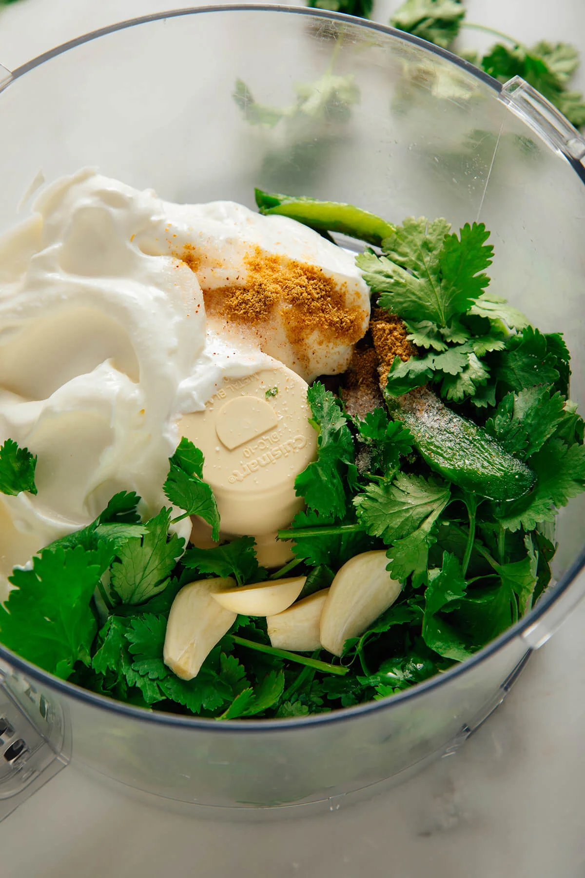 Spoon lifting creamy cilantro lime sauce from a jar